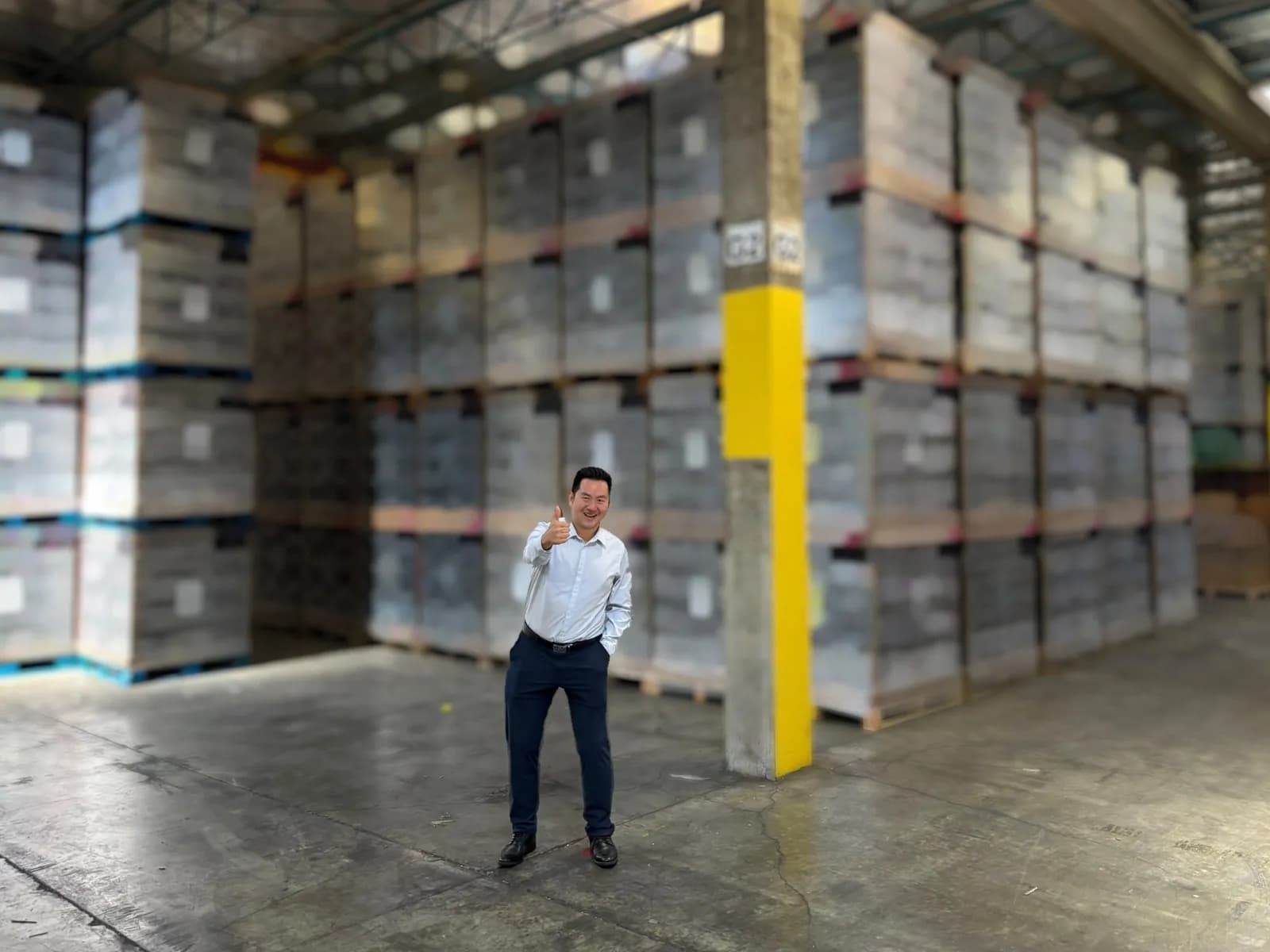 A man gives a thumbs-up in front of rows of wrapped pallets of socks from the program on the warehouse floor